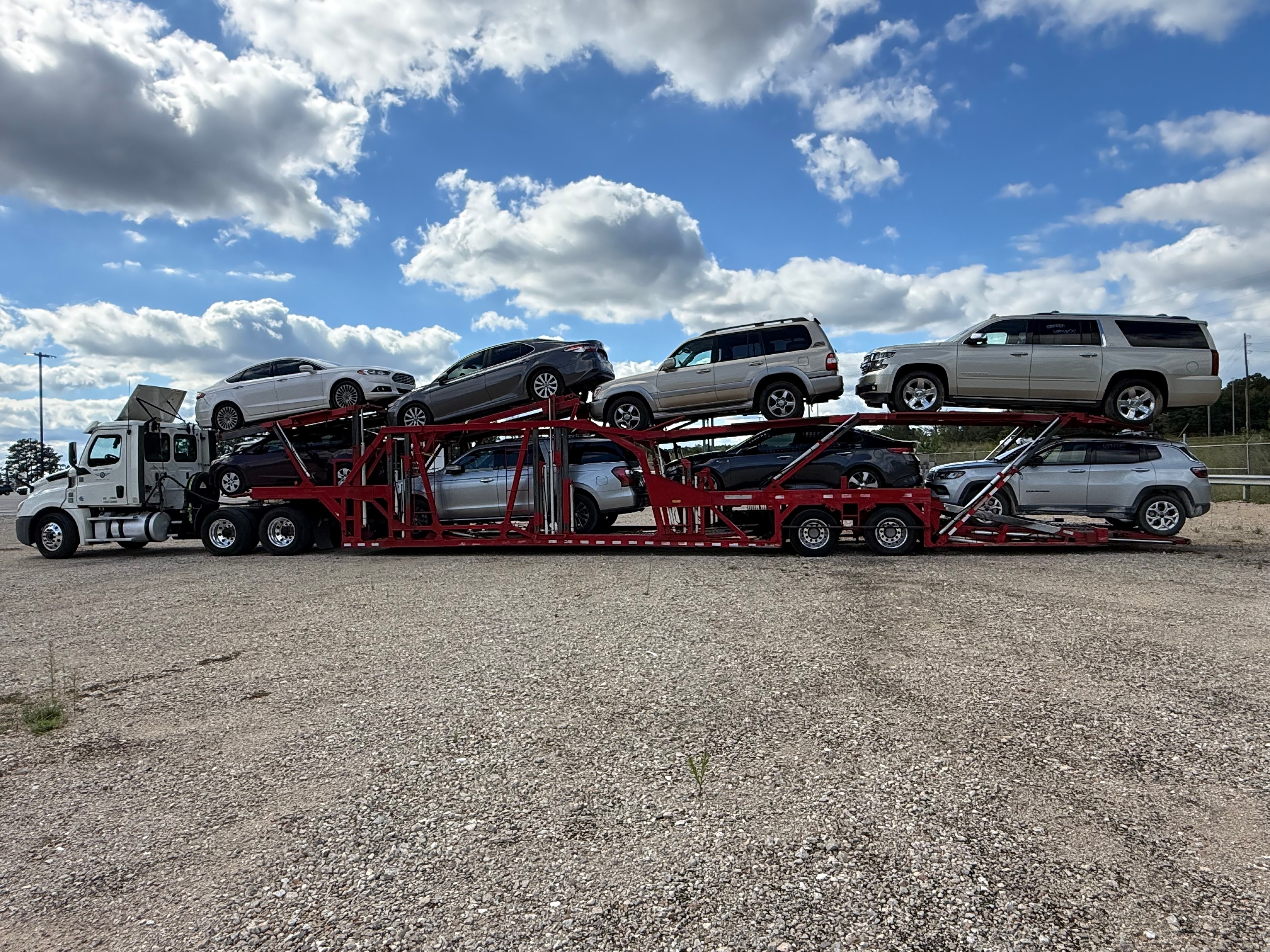Open car carrier transport truck with multiple vehicles on highway